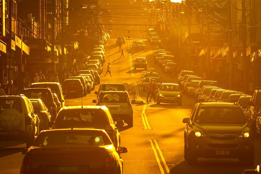 people corssing a busy road during a burning orange sunset