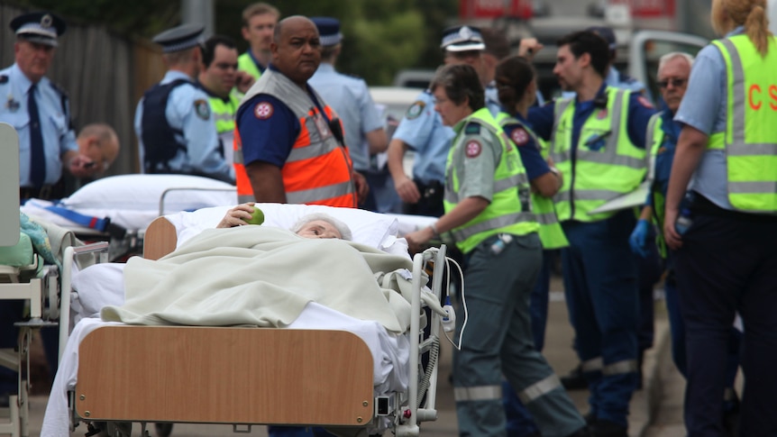 An elderly resident waits to be put in an ambulance after a fire at Quakers Hill Nursing Home
