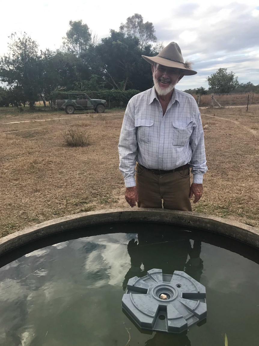 Del Richards smiles while standing behind a trough with his floating bird island in it.