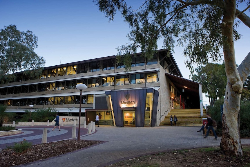 Students walk past Murdoch University's library at dusk.