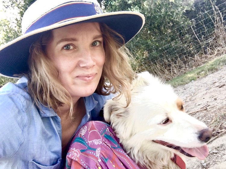 Lizzie Strick in her school uniform and hat taking a selfie with her white dog.