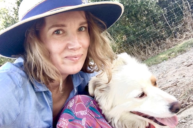 Lizzie Strick in her school uniform and hat taking a selfie with her white dog.
