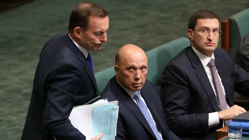 Peter Dutton and Julian Leeser look up at Tony Abbott as he walks past