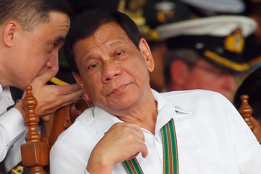 Philippine President Rodrigo Duterte listens to his Special Assistant during an army ceremony.