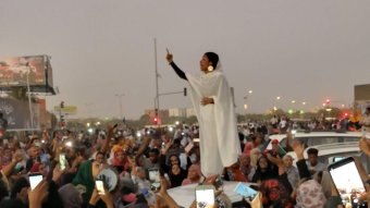 A woman stands on top of a car amid protests in the Sudanese capital of Khartoum, leading anti-regime chants.