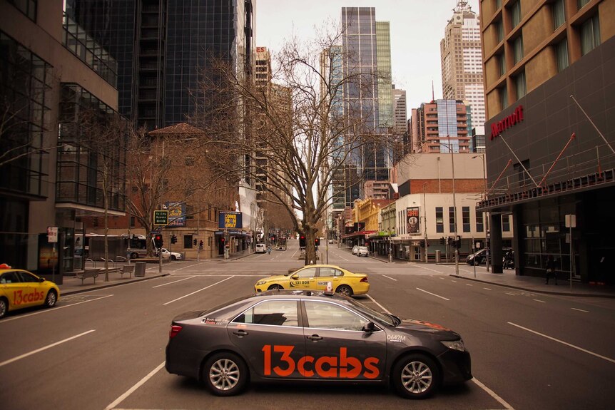 A Melbourne city street is empty of traffic, with just a few parked taxis.