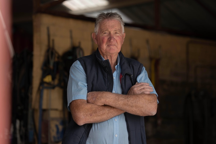 A man folds his arms in a stable.