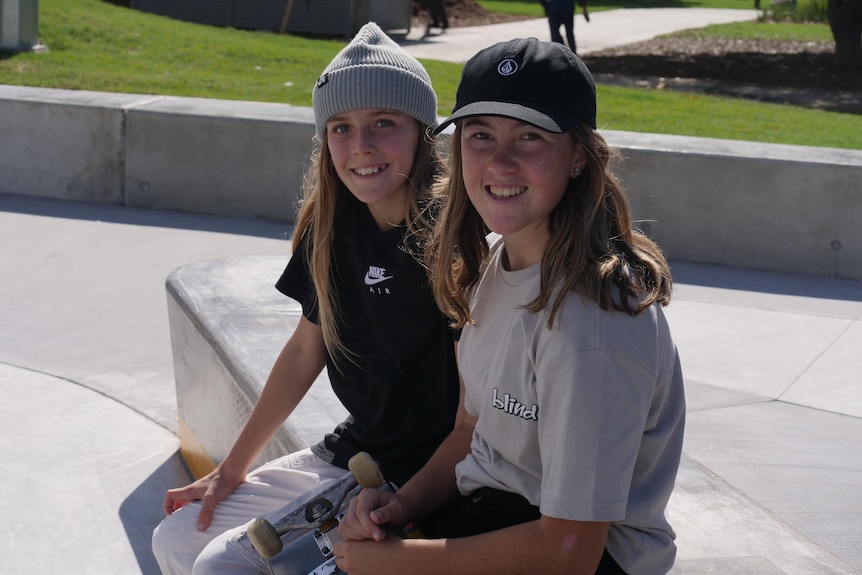 two girls sitting in a skate park