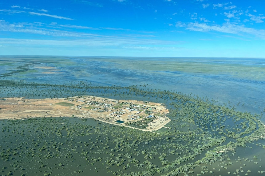 An aerial shot of a small town that has become an island due to floodwaters surrounding it.