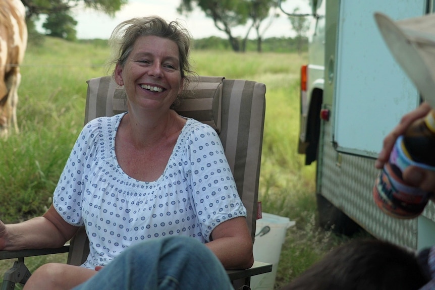 A woman in the bush laughing.