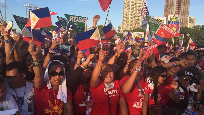 Supporters of Rodrigo Duterte wave flags and cheer.