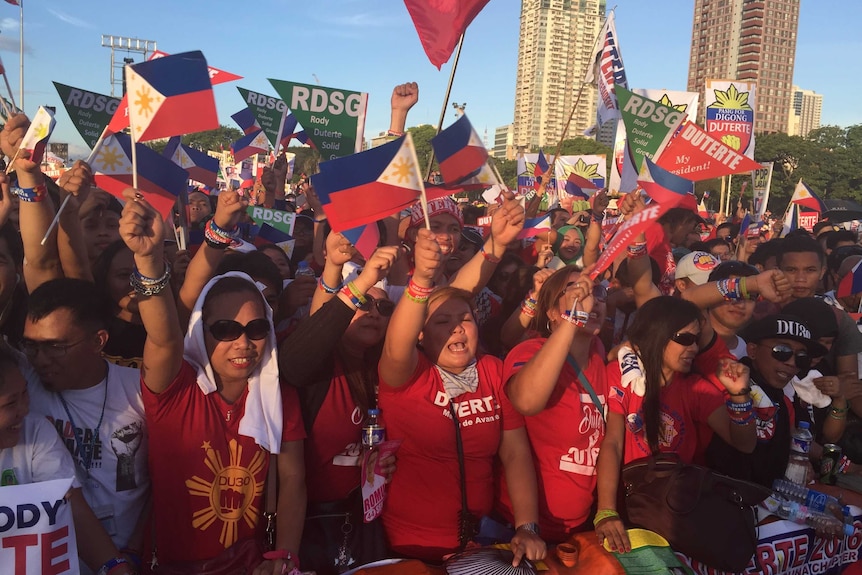 Supporters of Rodrigo Duterte wave flags and cheer.