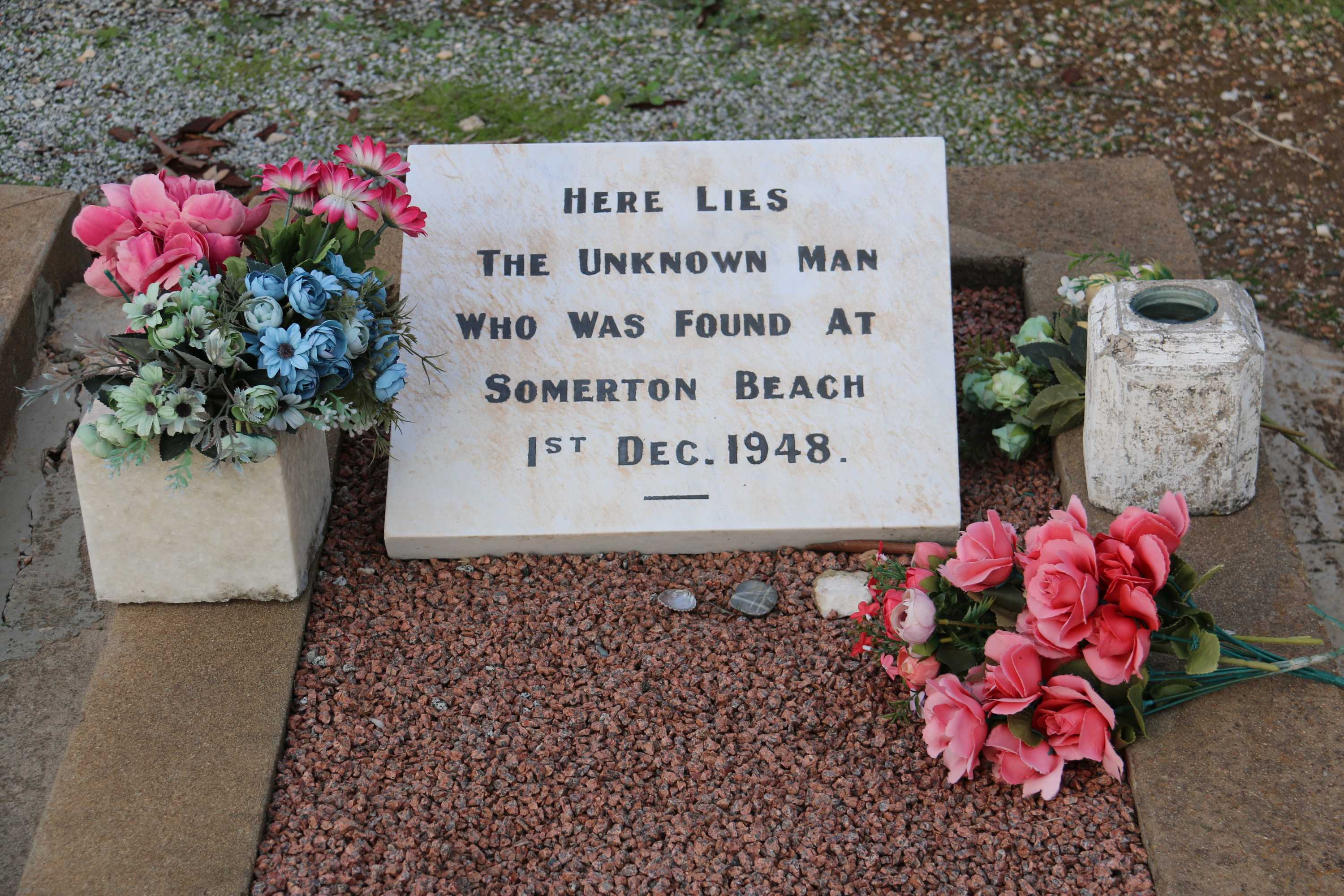 Stone slab on a grave with flowers around it