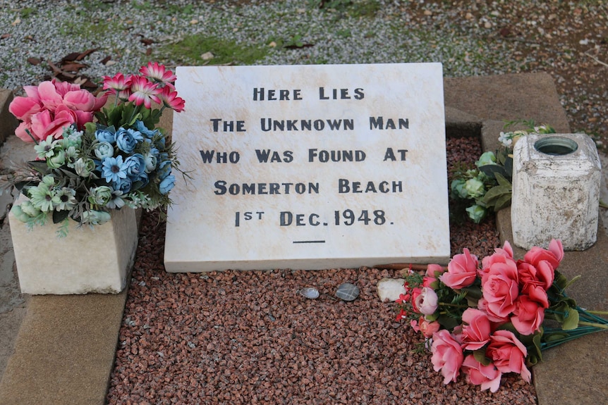 Stone slab on a grave with flowers around it