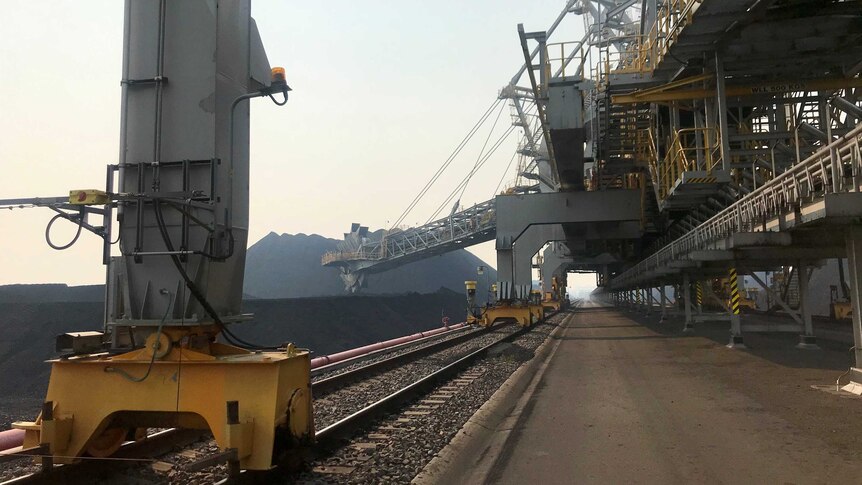 Large machinery alongside coal stockpiles.