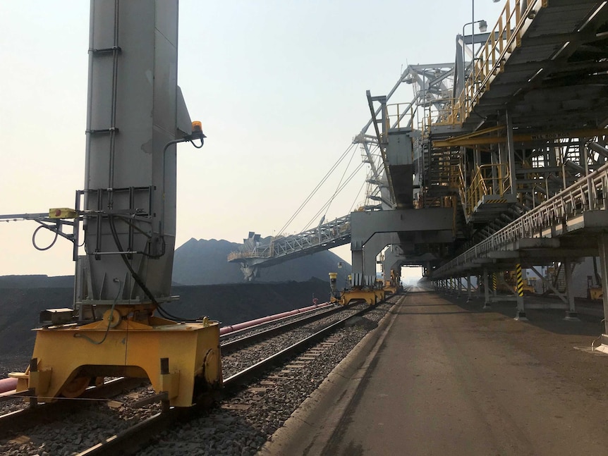 Large machinery alongside coal stockpiles.