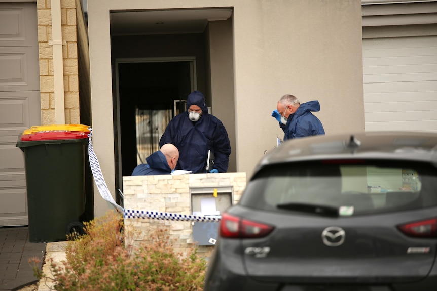 Three forensics officers wearing suits and masks outside a house