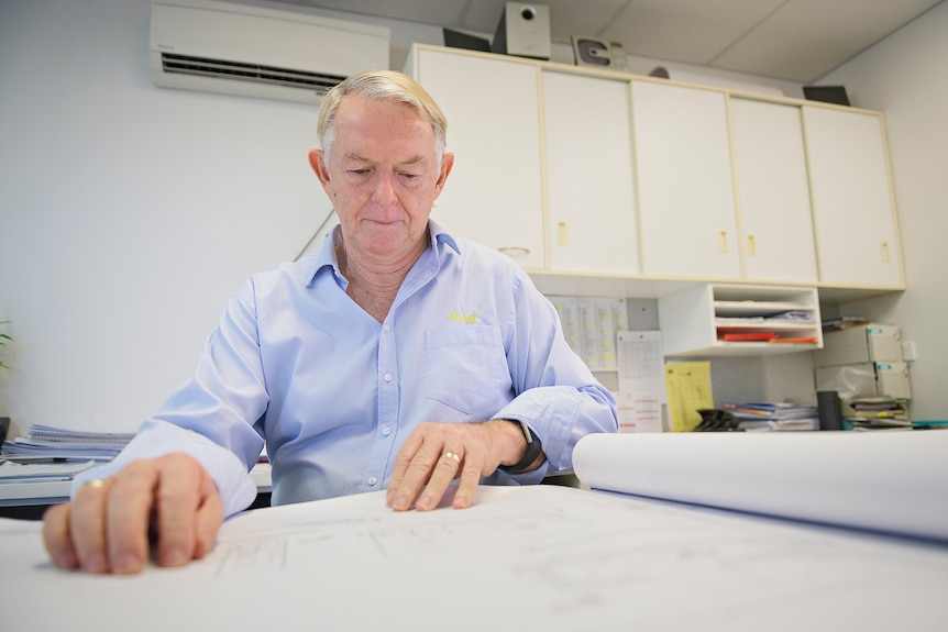 Neil Sunners, managing director of Sunbuild, sits at his office desk looking at papers.