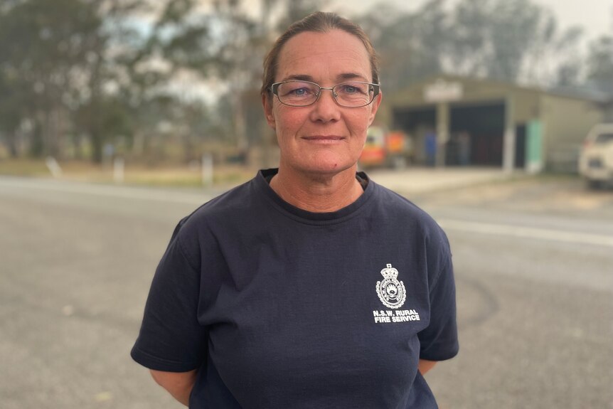 Shari Bent with the Willawawrrin Rural Fire Service stands in a navy uniform in front of the fire station