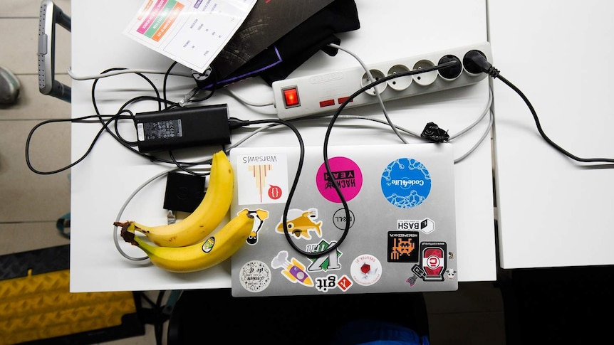 A laptop, charging cables and snacks on a desk