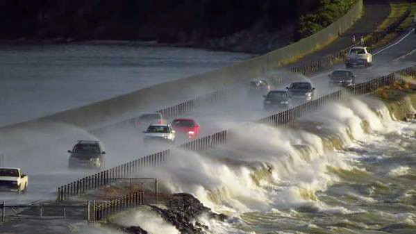 Waves crash over cars on the Midway Point causeway