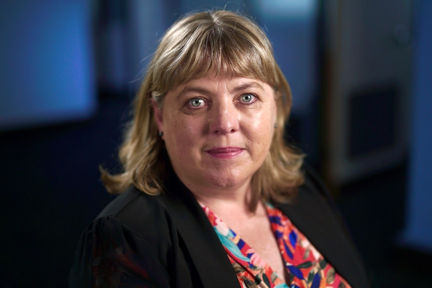 A woman wearing a black jacket over a multi-coloured top.