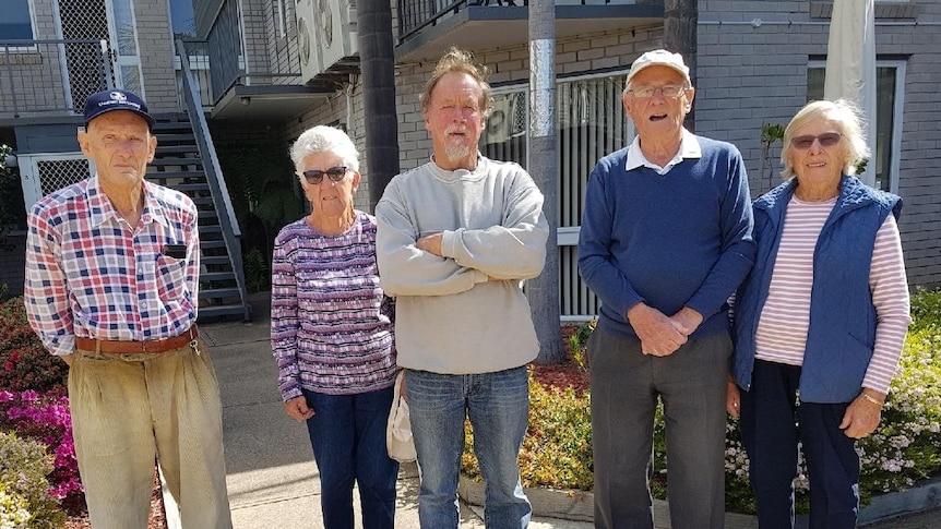 Five people stand in front of house 