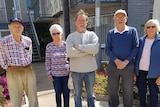 Five people stand in front of house 