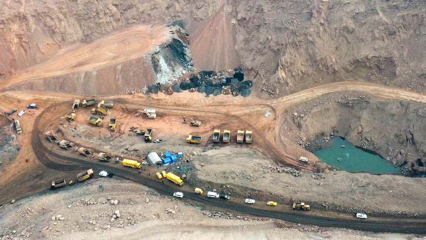 Aerial view of rescue vehicles near site of a collapsed open pit coal mine.