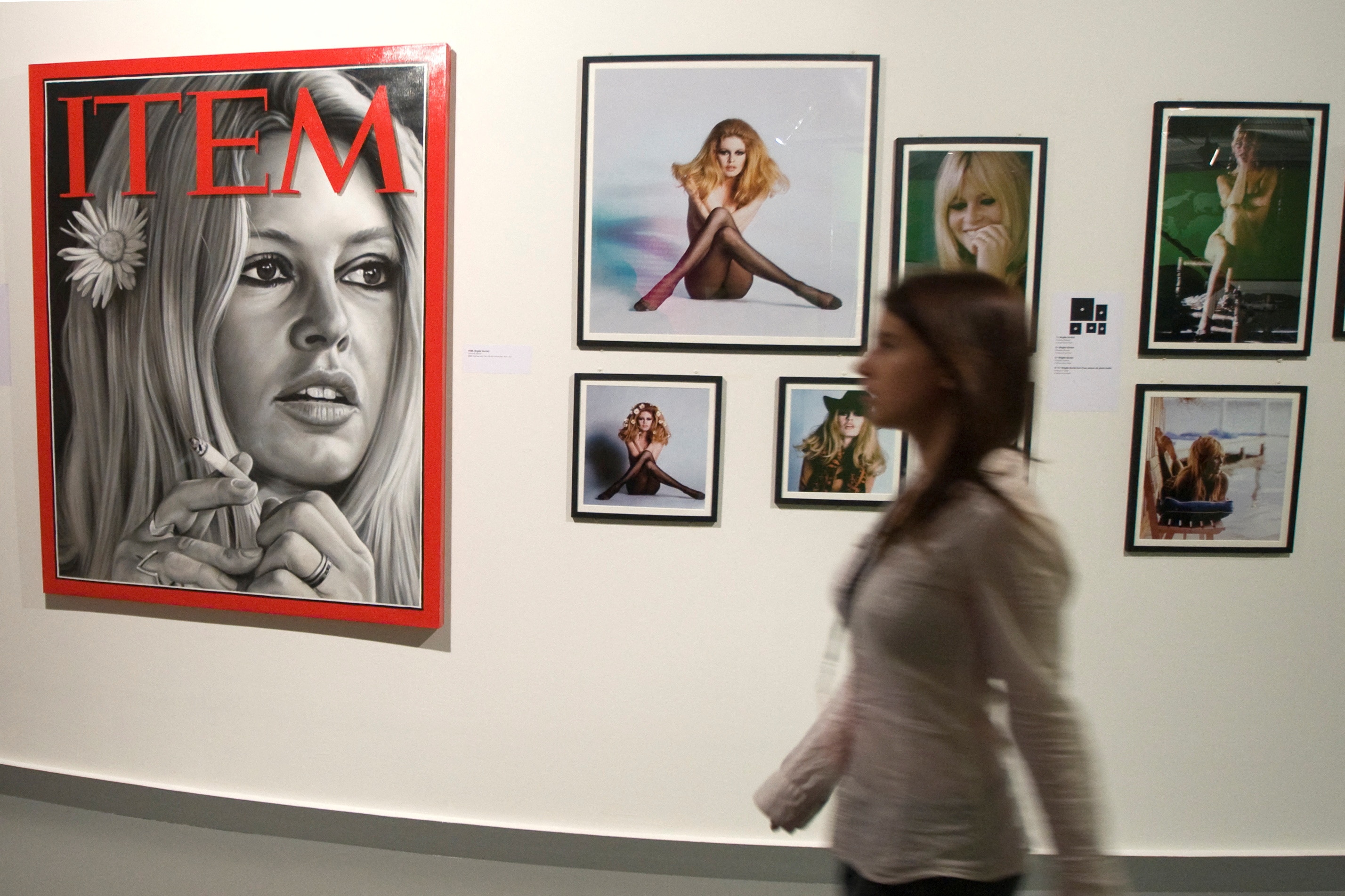 Una mujer pasa junto a una pared con fotografías de Brigitte Bardot. 