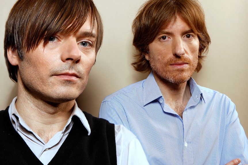 Close up image of two men with brown hair looking at the camera with straight faces