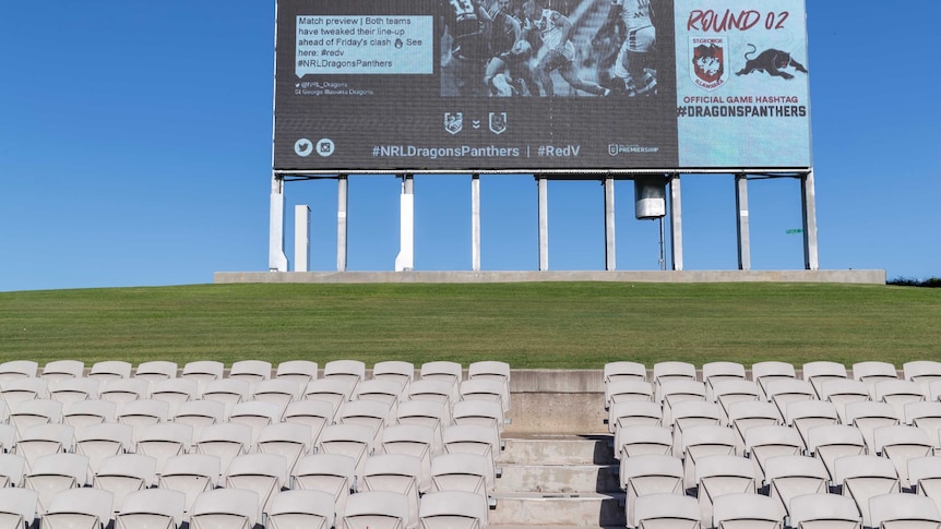 Empty seats and a scoreboard are seen near the grass banks of Jubilee Stadium