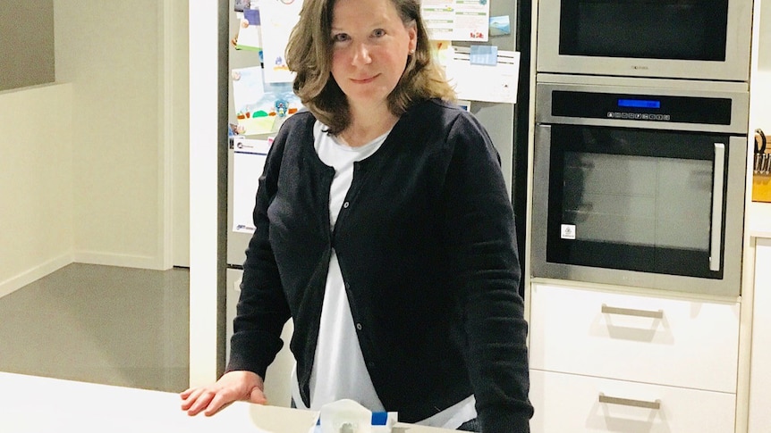 Michelle Cook in her kitchen of her Brisbane house with a packet of wipes on the bench.