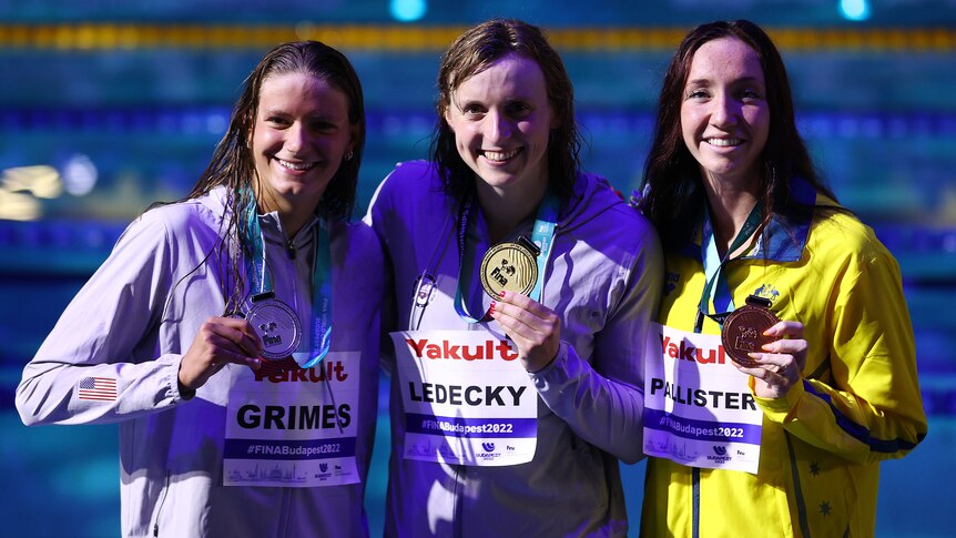 Katie Grimes, Katie Ledecky and Lani Pallister hold their medals and smile for the camera at the world swimming championships.
