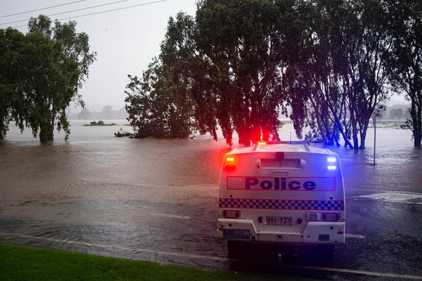 Une voiture de police se trouve sur une route inondée.