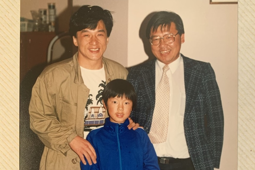 Two men and one boy posing for a photo in a Chinese restaurant.