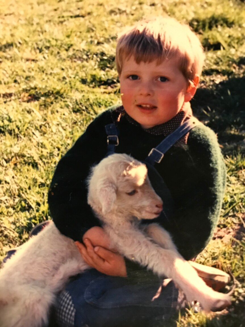 Young boy holding a white lamb. 
