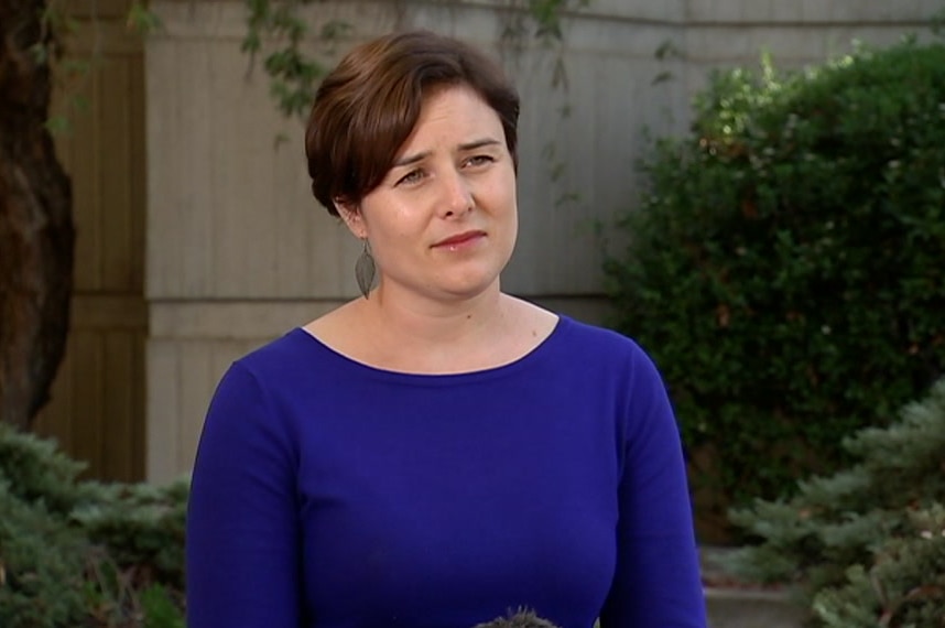 Lara Golding wearing a blue top standing in front of green trees