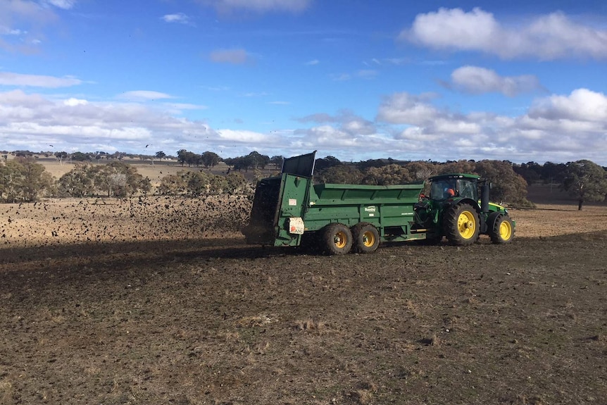 A tractor pulls a biosolid dispersing machine so the spread is wide and even