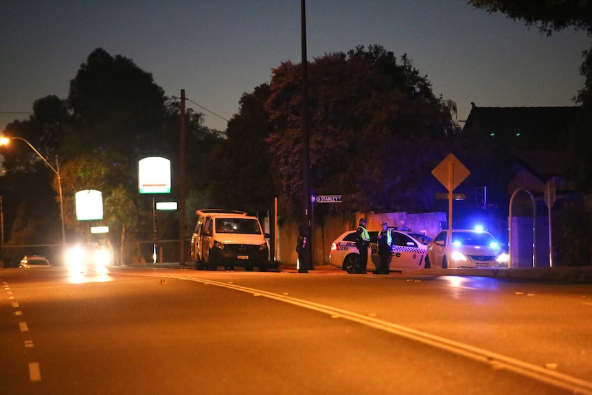 A wide shot showing police cars blocking a street at night in Mount Lawley.