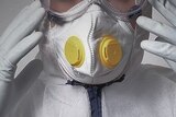 Person wearing face mask, gloves and biological hazard protection suit.