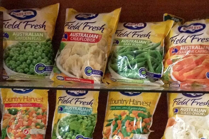 Packets of frozen vegetables on a shop shelf.