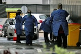 People wearing PPE in wintry conditions with cars