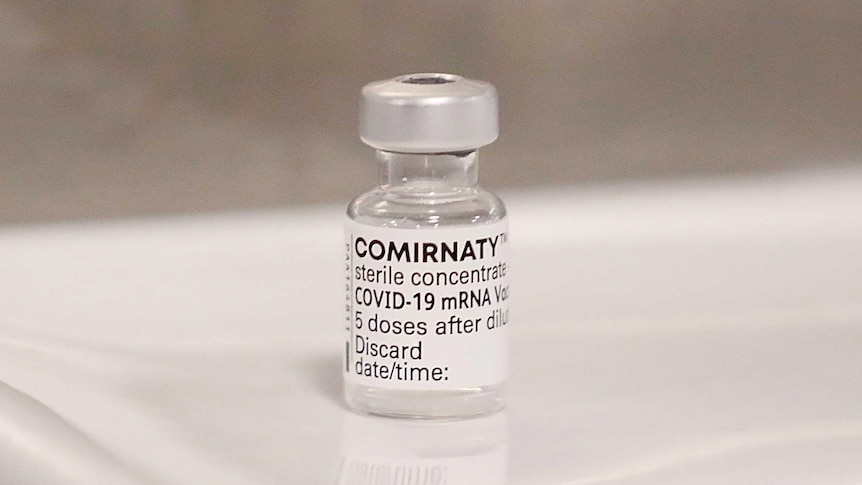 A vial of COVID-19 vaccine from Pfizer sits on a table