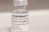A vial of COVID-19 vaccine from Pfizer sits on a table