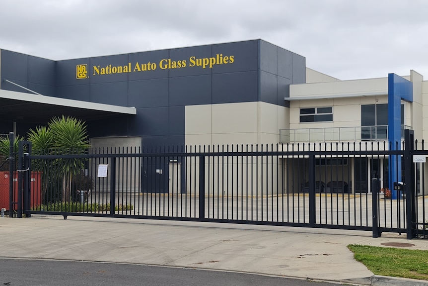 The exterior of a modern-looking warehouse with a closed gate.