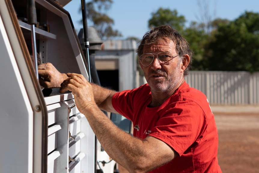 a man reaches into the toolbox of a toyota ute