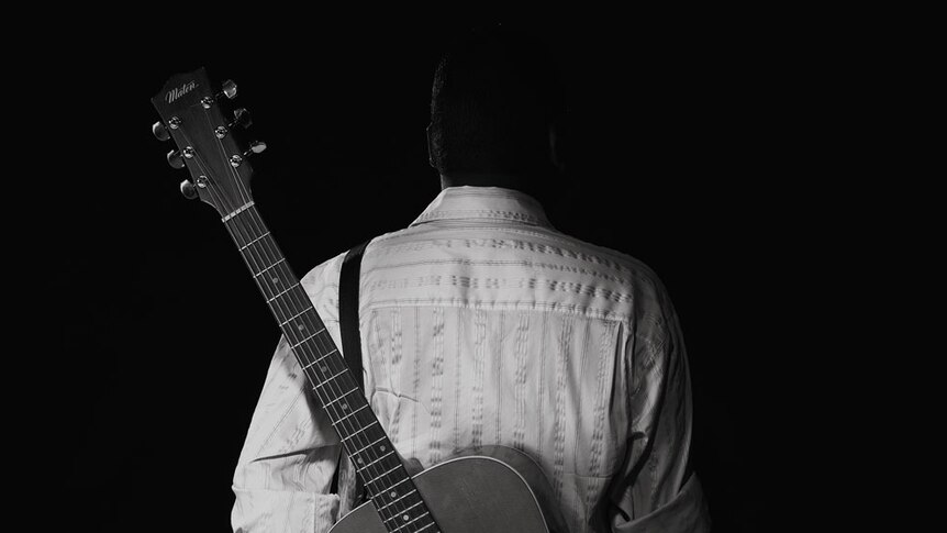 Dr G Yunupingu pictured from behind with his guitar.