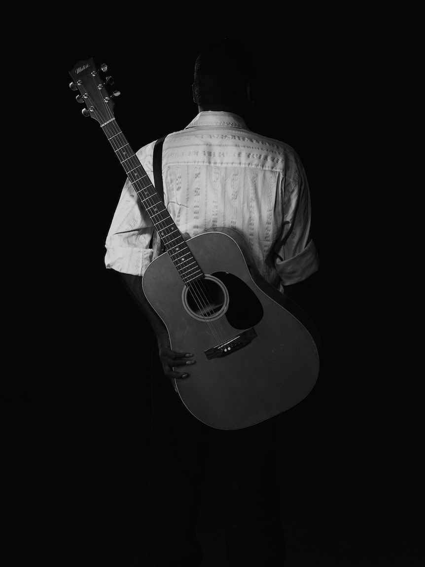 Dr G Yunupingu pictured from behind with his guitar.