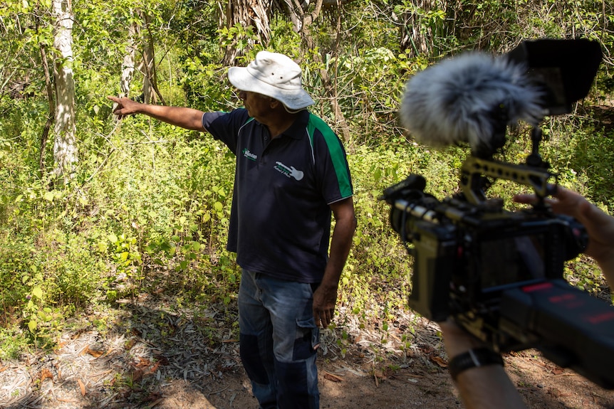 Traditional owner Brian Johnson points at plans and landscape while being filmed for a documentary.